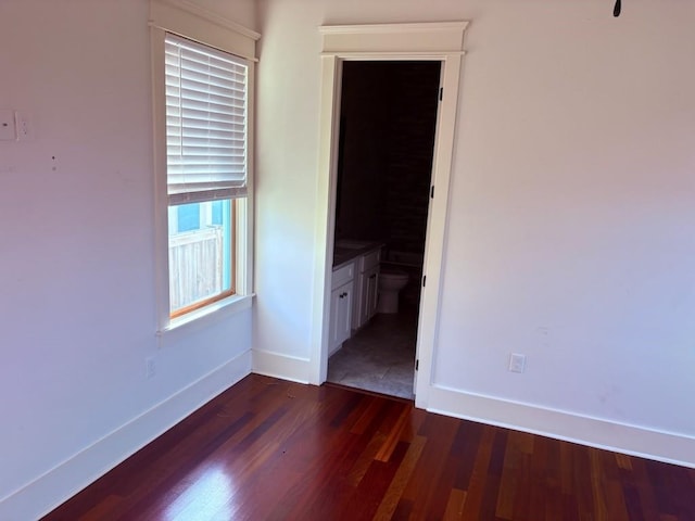 913 N Robertson St, New Orleans, LA 70116 - unfurnished bedroom with baseboards, dark wood-type flooring, and connected bathroom