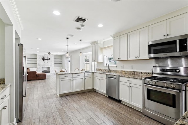 9108 Ormond Pl, River Ridge, LA 70123 - kitchen featuring appliances with stainless steel finishes, a sink, open floor plan, a fireplace, and a ceiling fan