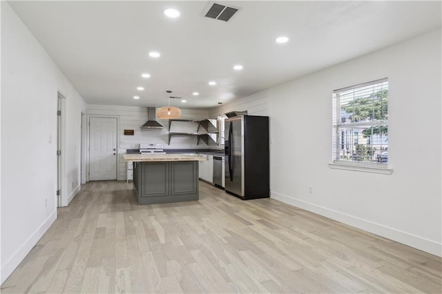 1401 Claiborne Dr, Jefferson, LA 70121 - kitchen featuring appliances with stainless steel finishes, wall chimney range hood, recessed lighting, a kitchen island, and light wood-style flooring