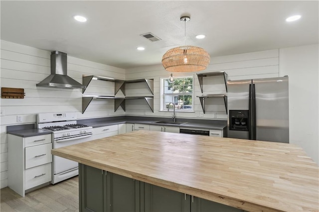 1401 Claiborne Dr, Jefferson, LA 70121 - kitchen featuring wooden counters, gas range gas stove, wall chimney exhaust hood, stainless steel refrigerator with ice dispenser, and a sink