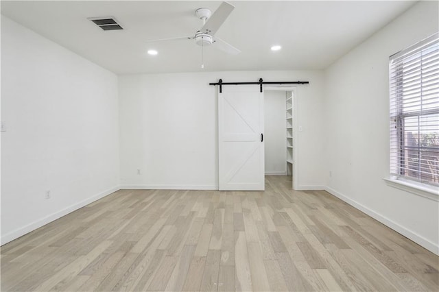 1401 Claiborne Dr, Jefferson, LA 70121 - unfurnished bedroom featuring a barn door, light wood-style flooring, recessed lighting, a walk in closet, and baseboards