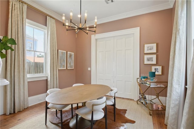 4119 S Liberty St, New Orleans, LA 70115 - dining space featuring light wood-style floors, a chandelier, ornamental molding, and baseboards