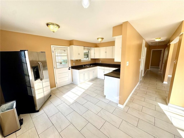 1523 W Dr, Westwego, LA 70094 - kitchen featuring stainless steel refrigerator with ice dispenser, dark countertops, white cabinetry, a sink, and baseboards