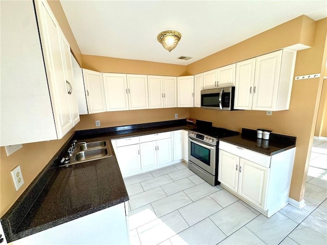 1523 W Dr, Westwego, LA 70094 - kitchen with stainless steel appliances, dark countertops, white cabinetry, and a sink