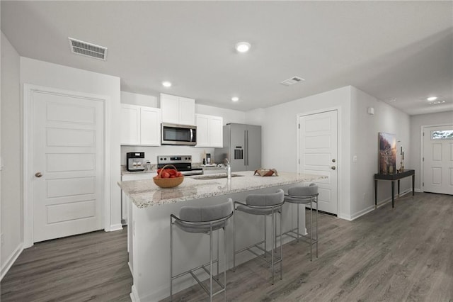 kitchen featuring stainless steel appliances, a sink, a kitchen island with sink, white cabinets, and dark wood-style flooring