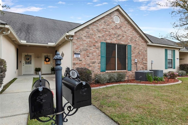 40145 Taylor Trl Unit 503, Slidell, LA 70461 - view of front facade with brick siding, a front lawn, a shingled roof, central air condition unit, and stucco siding