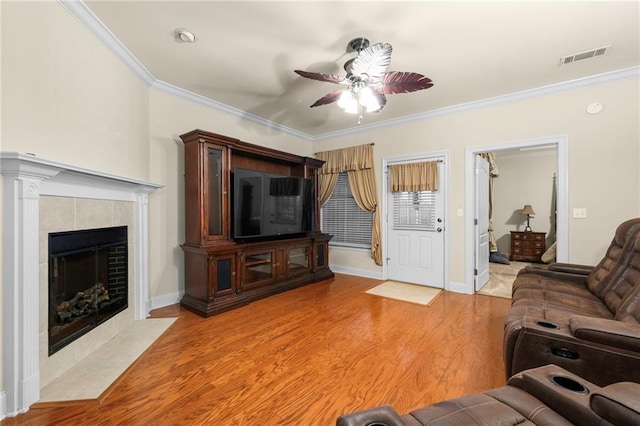 40145 Taylor Trl Unit 503, Slidell, LA 70461 - living room featuring a ceiling fan, ornamental molding, light wood-style floors, a tile fireplace, and baseboards