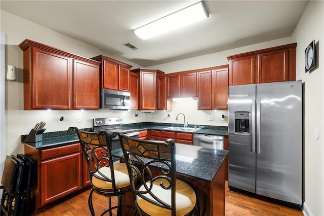 40145 Taylor Trl Unit 503, Slidell, LA 70461 - kitchen with stainless steel appliances, a sink, reddish brown cabinets, dark wood finished floors, and a kitchen island