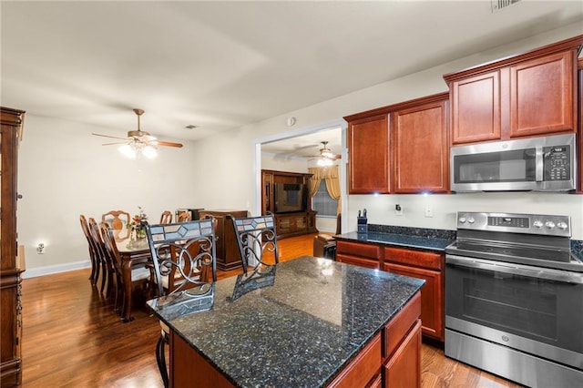 40145 Taylor Trl Unit 503, Slidell, LA 70461 - kitchen with stainless steel appliances, a ceiling fan, wood finished floors, a kitchen island, and dark stone counters