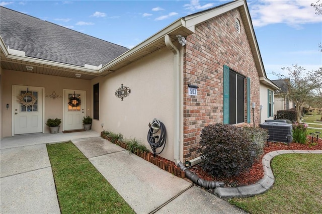40145 Taylor Trl Unit 503, Slidell, LA 70461 - view of home's exterior featuring brick siding, cooling unit, roof with shingles, and stucco siding