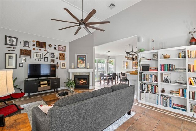22236 8th St, Abita Springs, LA 70420 - tiled living area with lofted ceiling, ceiling fan, a tiled fireplace, and a chandelier