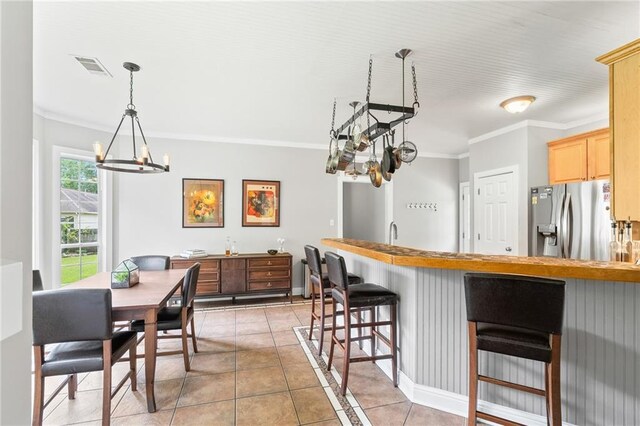 22236 8th St, Abita Springs, LA 70420 - kitchen featuring stainless steel fridge with ice dispenser, a chandelier, ornamental molding, a kitchen breakfast bar, and light tile patterned floors