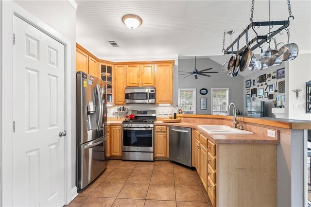 22236 8th St, Abita Springs, LA 70420 - kitchen featuring appliances with stainless steel finishes, a peninsula, light tile patterned floors, ceiling fan, and glass insert cabinets