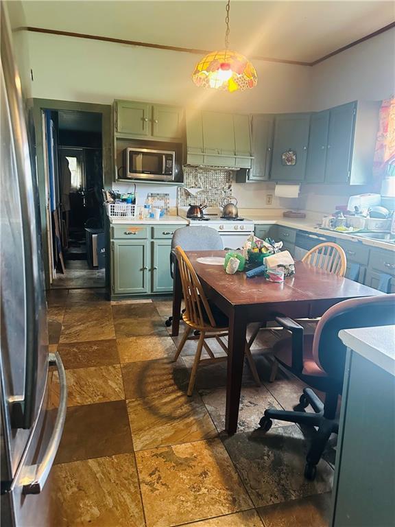 307 Diana St, New Orleans, LA 70114 - kitchen with green cabinets, stainless steel appliances, light countertops, and dark stone finish flooring