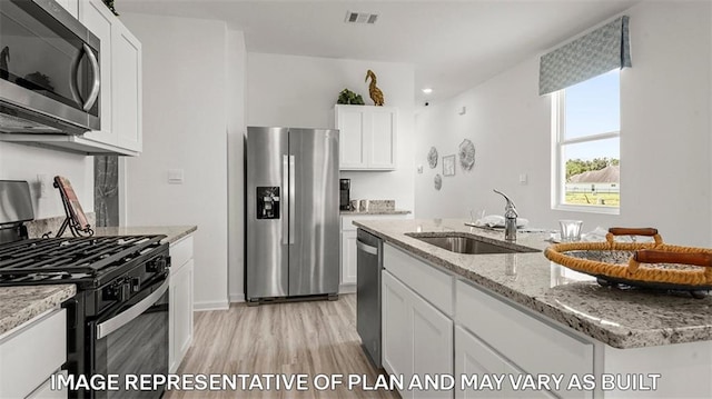 311 Holmes Blvd, Terrytown, LA 70056 - kitchen featuring appliances with stainless steel finishes, a sink, light wood finished floors, white cabinetry, and light stone counters