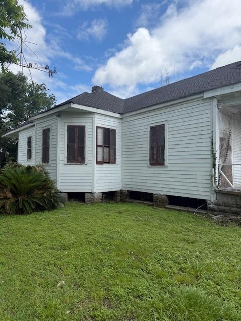 5123 Chartres St, New Orleans, LA 70117 - back of property with a lawn and roof with shingles