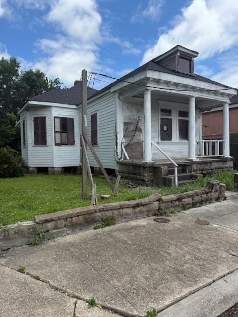 5123 Chartres St, New Orleans, LA 70117 - view of front facade with a front lawn and a porch