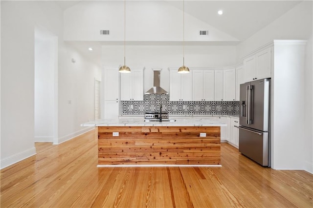 5519 Wingate Dr, New Orleans, LA 70122 - kitchen featuring high end refrigerator, wall chimney range hood, decorative backsplash, white cabinets, and light wood finished floors