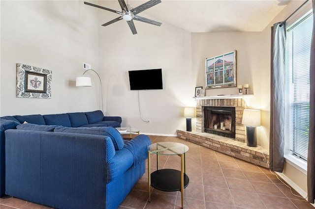 tiled living area featuring ceiling fan, plenty of natural light, a fireplace, baseboards, and high vaulted ceiling