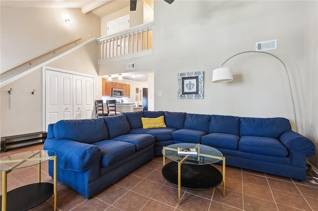 living area with dark tile patterned flooring, high vaulted ceiling, and beam ceiling