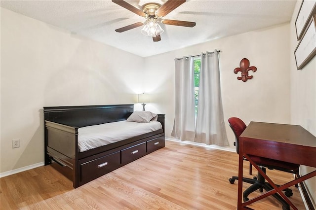 bedroom featuring light wood-style floors, baseboards, a ceiling fan, and a textured ceiling