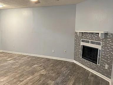 unfurnished living room with wood finished floors, baseboards, and a tiled fireplace