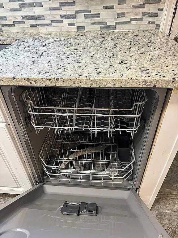 kitchen view of dishwasher, tasteful backsplash, and light stone counters