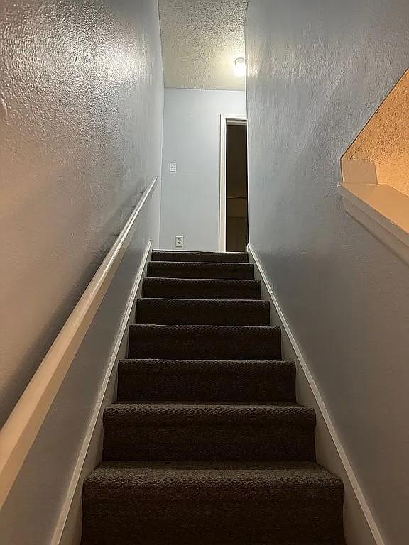 staircase featuring a textured ceiling