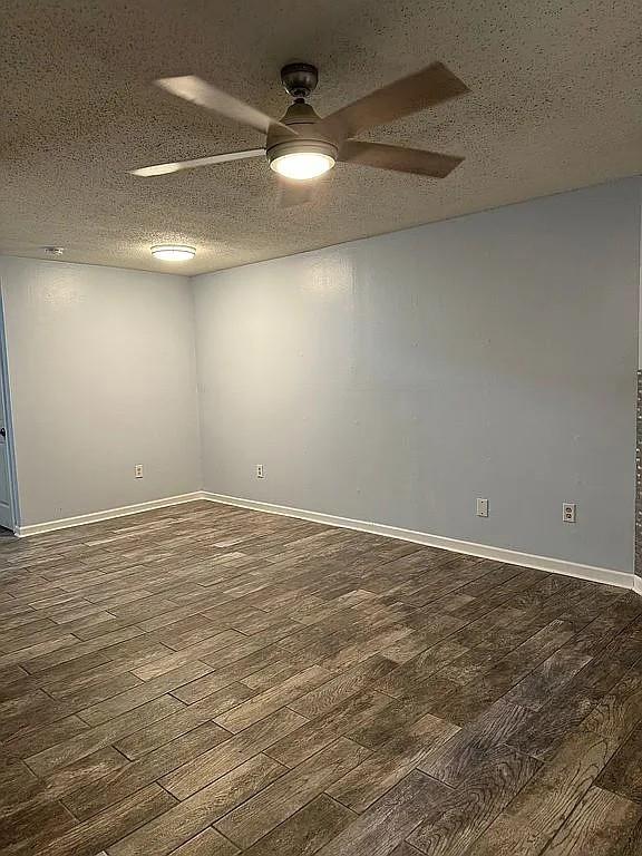 spare room featuring dark wood-style floors, ceiling fan, a textured ceiling, and baseboards