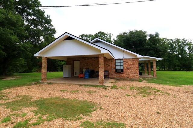 42073 Farlow Ln, Ponchatoula, LA 70454 - view of side of property featuring a lawn, a carport, brick siding, dirt driveway, and a patio area