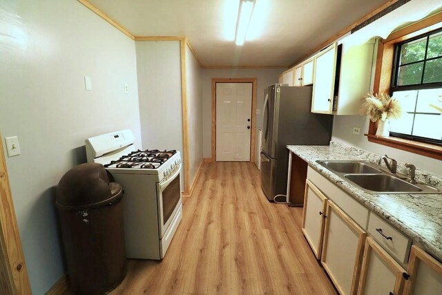 42073 Farlow Ln, Ponchatoula, LA 70454 - kitchen featuring white range with gas stovetop, a sink, light wood-style floors, freestanding refrigerator, and baseboards