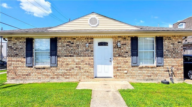301 E Liberaux St, Chalmette, LA 70043 - view of front facade featuring a front lawn, brick siding, and a shingled roof