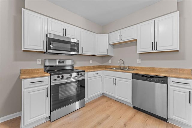 301 E Liberaux St, Chalmette, LA 70043 - kitchen featuring appliances with stainless steel finishes, a sink, light wood-style flooring, and white cabinetry
