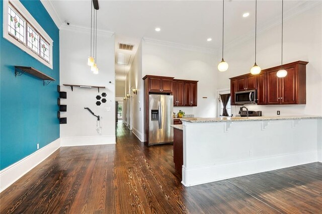 1607 N Villere St, New Orleans, LA 70116 - kitchen with appliances with stainless steel finishes, a peninsula, a kitchen bar, ornamental molding, and pendant lighting