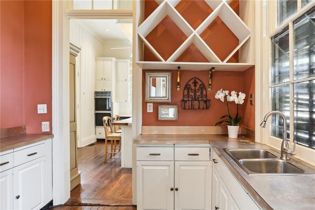 919 Robert St, New Orleans, LA 70115 - kitchen with a sink, white cabinetry, dark wood-style flooring, ornamental molding, and light countertops