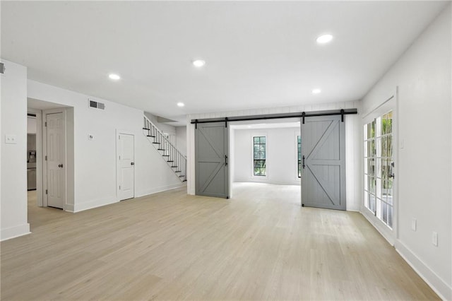 48 Bleu Lake Dr, Covington, LA 70435 - unfurnished living room with a barn door, light wood-style flooring, recessed lighting, and baseboards