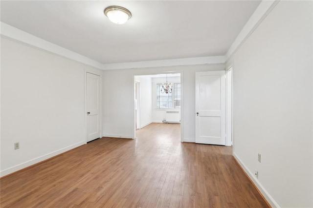 5402 St Charles Ave, New Orleans, LA 70115 - unfurnished room featuring radiator heating unit, a chandelier, wood finished floors, and baseboards