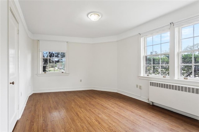 5402 St Charles Ave, New Orleans, LA 70115 - unfurnished room with radiator, plenty of natural light, wood finished floors, and baseboards