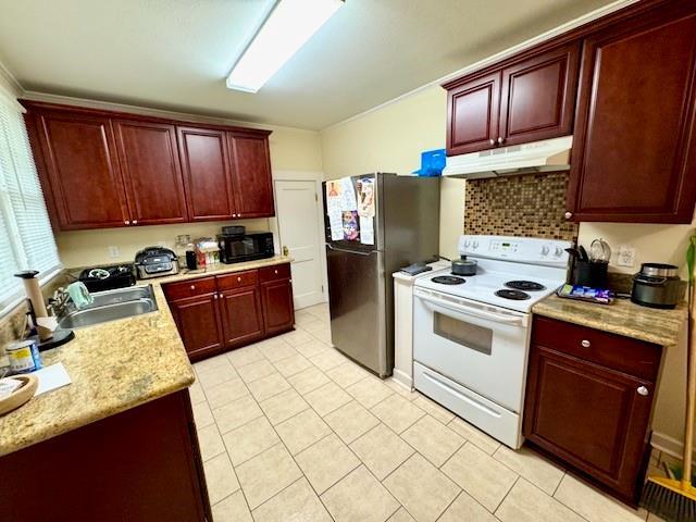 1742 4th St, Slidell, LA 70458 - kitchen featuring white electric range, under cabinet range hood, reddish brown cabinets, and freestanding refrigerator