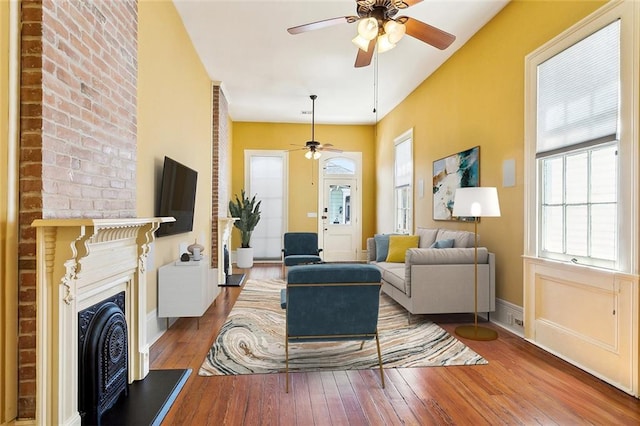 3119 Dauphine St, New Orleans, LA 70117 - living room featuring ceiling fan, a fireplace with raised hearth, and hardwood / wood-style floors