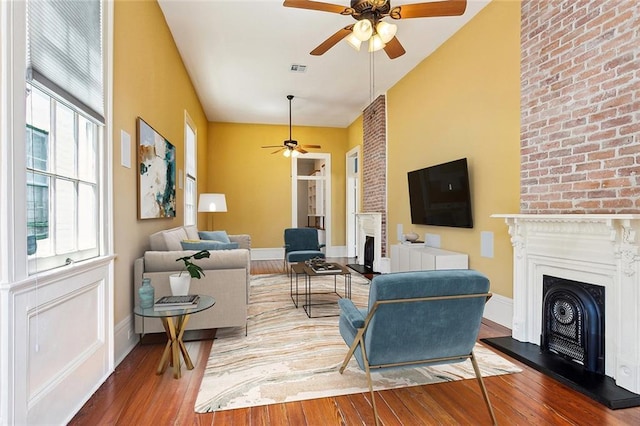 3119 Dauphine St, New Orleans, LA 70117 - living area featuring a fireplace with raised hearth, ceiling fan, and hardwood / wood-style floors