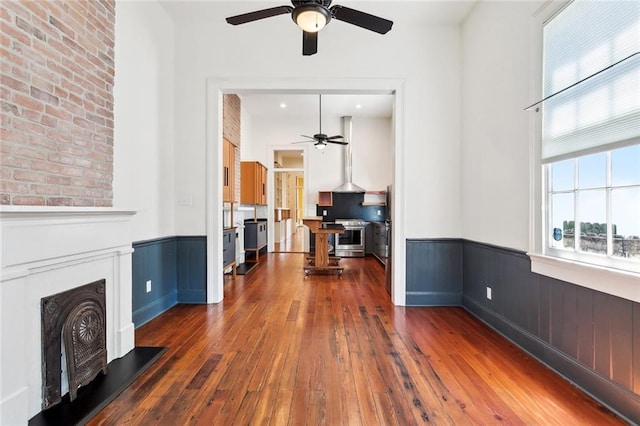 3119 Dauphine St, New Orleans, LA 70117 - unfurnished living room featuring ceiling fan, a wainscoted wall, and dark wood-style floors