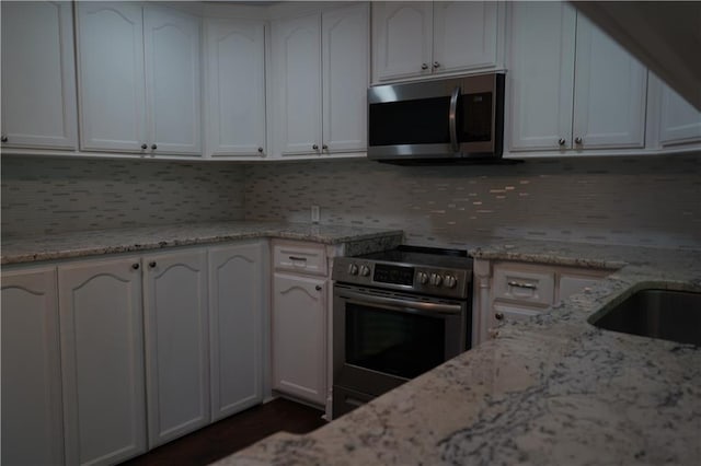 24819 S Walker Rd, Denham Springs, LA 70726 - kitchen featuring stainless steel appliances, light stone countertops, decorative backsplash, and white cabinets