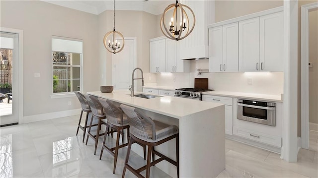 811 Rosa Ave, Metairie, LA 70005 - kitchen with a chandelier, stainless steel appliances, a sink, premium range hood, and a kitchen island with sink
