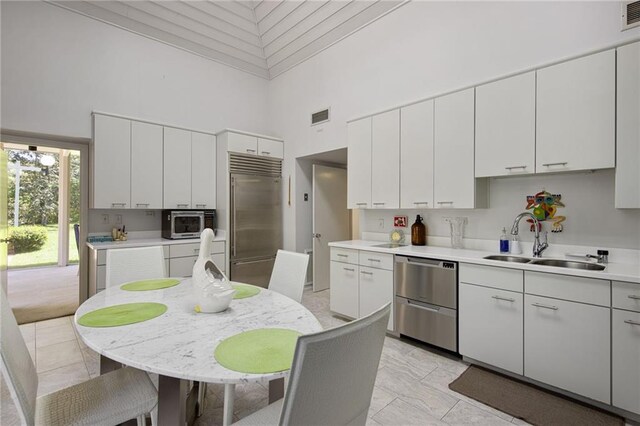 1450 Pine Tree Rd, Opelousas, LA 70570 - kitchen featuring a towering ceiling, appliances with stainless steel finishes, a sink, light countertops, and white cabinetry