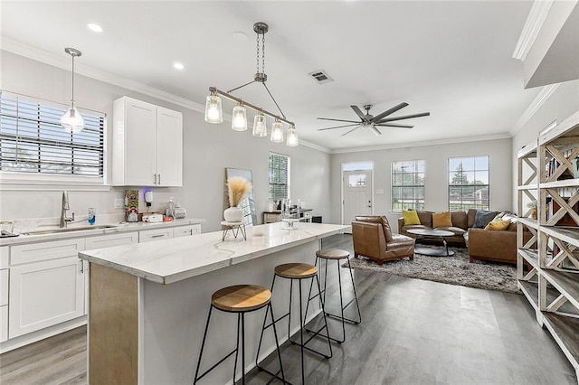 142325 Lamanche St, New Orleans, LA 70117 - kitchen featuring a sink, a ceiling fan, light wood-type flooring, a breakfast bar area, and a kitchen island