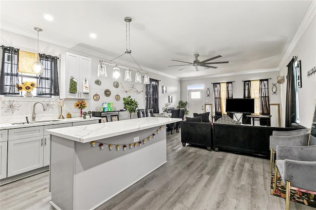 142325 Lamanche St, New Orleans, LA 70117 - kitchen featuring a sink, a ceiling fan, light wood-style flooring, hanging light fixtures, and crown molding
