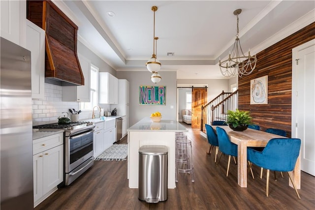 415 N Dupre St, New Orleans, LA 70119 - kitchen with appliances with stainless steel finishes, a barn door, dark wood-type flooring, custom range hood, and crown molding