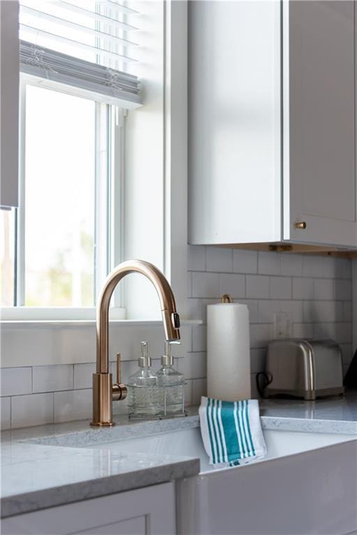 415 N Dupre St, New Orleans, LA 70119 - detailed view of decorative backsplash, white cabinetry, and light stone countertops