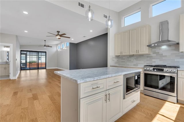 6100 Duplessis St, New Orleans, LA 70122 - kitchen featuring stainless steel appliances, wall chimney range hood, light wood-style flooring, decorative backsplash, and a ceiling fan